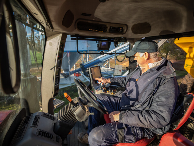 Farmer sitting in tractor using a device connected via wi-fi to a Zetifi ZetiRover
